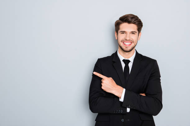 Young handsome businessman with beaming smile pointing with finger